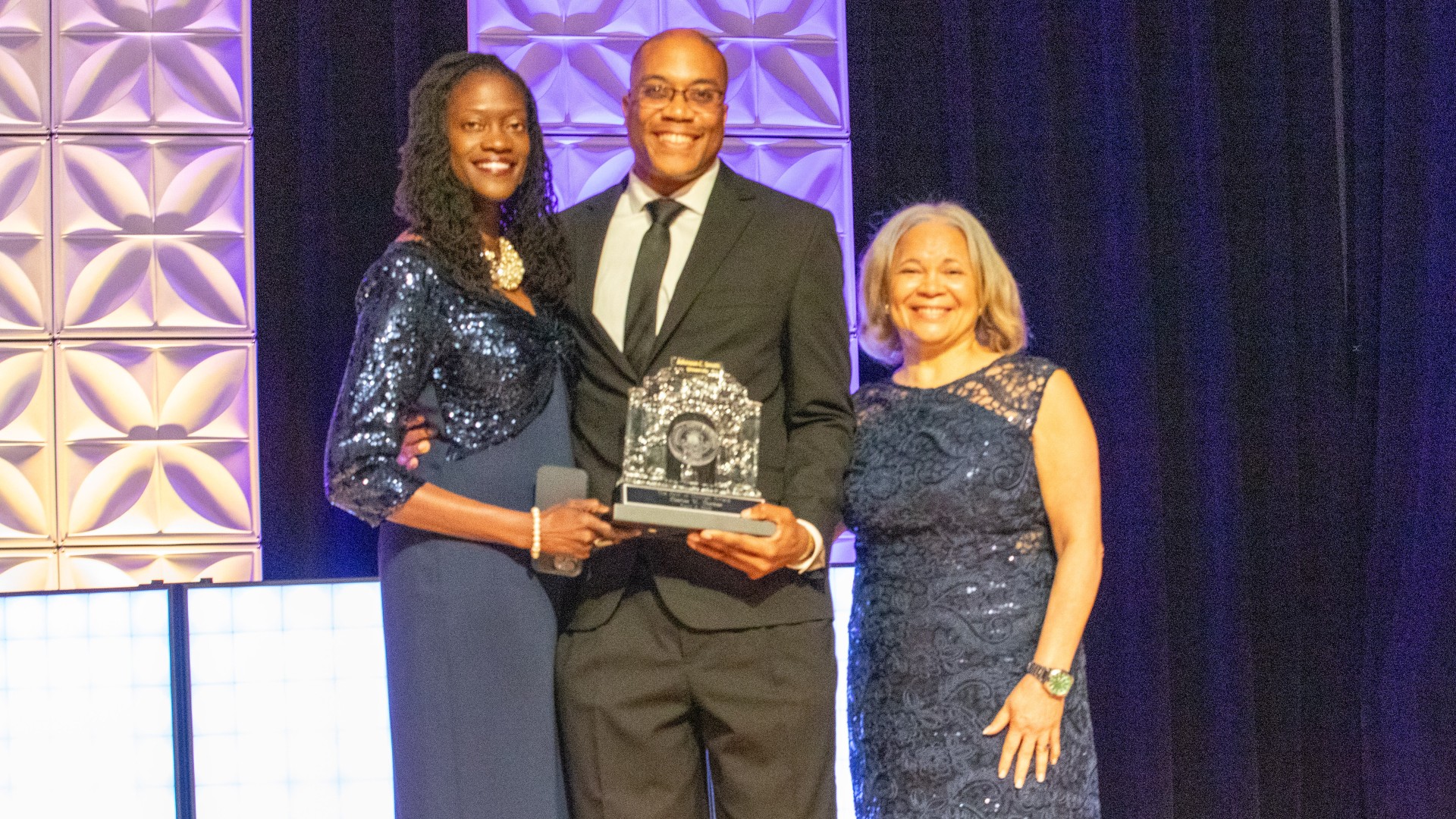 Dr. Kinloch, Charles Thomas and Mayor Vi Lyles posing with the award